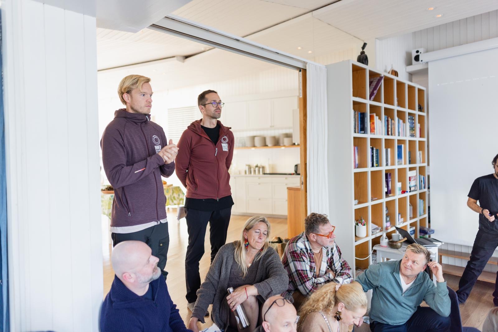 A workshop session in a bright room with bookshelves, participants engaged in dialogue and learning